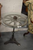 An unusual glass topped wagon wheel occasional table on a cast iron base.