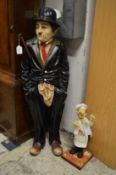 A painted composite floor standing model of Charlie Chaplin together with a similar smaller one of a
