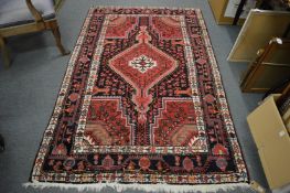 A Persian style rug, red and blue ground with geometric design, 220cm x 135cm.
