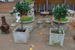 A pair of faux lead square shaped planters, each containing an artificial shrub.