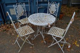 White painted wrought iron patio table with four folding chairs.