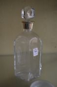 A glass decanter with silver collar.