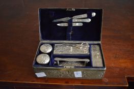 A white metal box with chased and decoration containing dressing table and manicure items.