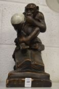 An amusing pottery model of a monkey seated on books holding a skull in his hand, signed Darwin.