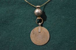 A coin and ball pendant with chain.