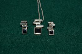 A silver pendant and chain and earrings.