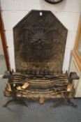A large cast iron fireback with pair of firedogs, cast iron grate and fireside tools.