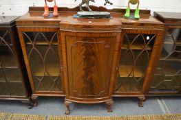 A mahogany display cabinet with bow fronted panelled central door flanked by a pair astragal