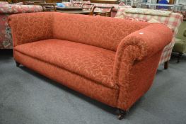 A Victorian three seater Chesterfield settee upholstered in a red ground fabric.