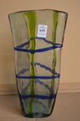 A large triangular shaped green and blue decorated glass vase.
