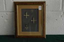 Three small bronze crucifixes, framed and glazed.
