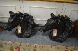 A pair of black painted plaster models of horses heads.