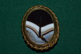 A large yellow metal and agate oval shaped brooch (old repairs).