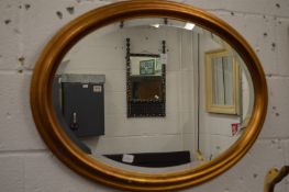 A gilt framed oval wall mirror.