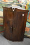 A 19th century oak bow fronted hanging corner cupboard.