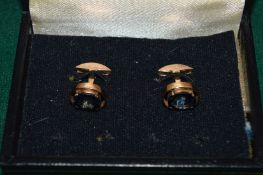 A pair of yellow metal cufflinks, each set with an oval sapphire.