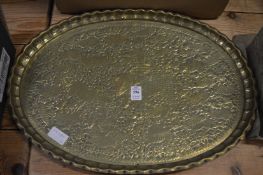 An embossed brass tray and other items.