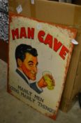 A novelty metal sign 'Man Cave'.