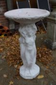 A white painted reconstituted stone garden bird bath with female figural supports.