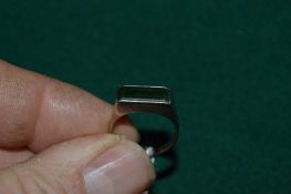 An unusual 18ct white gold ring set with a rectangular green stone, possibly emerald.