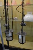 A pair of wrought iron and frosted glass hall lanterns.