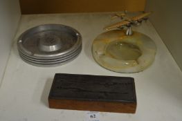 An alabaster ashtray mounted with a model of an aeroplane and two other items.