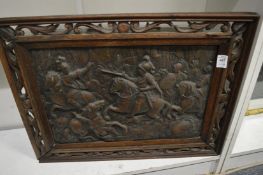 An embossed metal plaque in a carved and pierced frame.