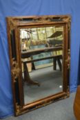 A decorative ebonised and gilt framed rectangular wall mirror.