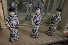A set of three Chinese blue and white figures of scholars.