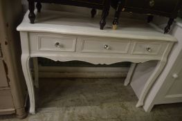 A white painted three drawer side table.