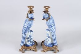 A GOOD PAIR OF BLUE AND WHITE PORCELAIN PARROT CANDLESTICKS on gilt metal bases. 14ins high.
