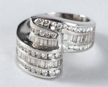 A 14CT WHITE GOLD DIAMOND CROSS OVER RING.