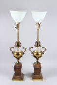 A PAIR OF GLASS URN SHAPED LAMPS on square bases.