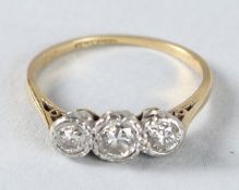 AN 18CT GOLD THREE STONE DIAMOND RING.