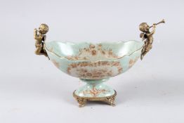 A PORCELAIN BOWL with two gilt metal cupids. 12ins wide.