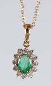 AN 18CT GOLD, OVAL EMERALD AND DIAMOND PENDANT AND CHAIN.