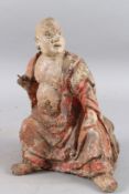 A CARVED WOOD AND POLYCHROME STATUE OF A SEATED MONK OF ARHAT, sitting cross legged. 28cms high.