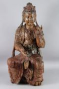 A LARGE CARVED AND PAINTED WOOD FIGURE OF GUANYIN sitting in a relaxed nude, with one knee raised,