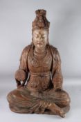 A LARGE CARVED WOOD FIGURE OF GUANYIN sitting cross legged, hands missing. 94cms high x 58cms wide.