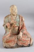 A CARVED WOOD AND POLYCHROME STATUE OF A SEATED MONK OF ARHAT, sitting cross legged. 28cms high.