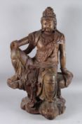 A CHINESE CARVED AND GILDED WOODEN FIGURE OF GUANYIN sitting on a rocky throne, with headdress and