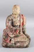 A CARVED WOOD AND POLYCHROME STATUE OF A SEATED MONK OF ARHAT, sitting cross legged. 30cms high.