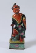 A JAPANESE POTTERY BUDDHA, hand painted with red face and beard. 20cms high.