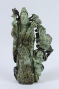 A GOOD LARGE CHINESE CARVED SOAPSTONE FIGURE OF A GUANYIN, a young boy by his side. 37cms high.