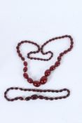 TWO CHERRY AMBER BEAD NECKLACES. 80cms and 40cms long. 95grams.