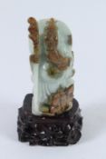 A CHINESE TWO COLOUR JADE CARVING OF GUAN GONG holding a staff. 12cms high, on a wooden base.
