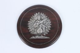 A FINE INDIAN SILVER HINDU DEITY on a wooden plaque. 23cms diameter.
