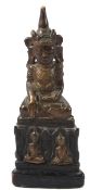 A CARVED WOOD FIGURE, PHRA NGAN, Thailand, sitting cross-legged on a throne. 30cms high.
