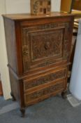 A small carved oak cupboard with drawers below.