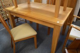 A modern oak extending dining table with two leaves.